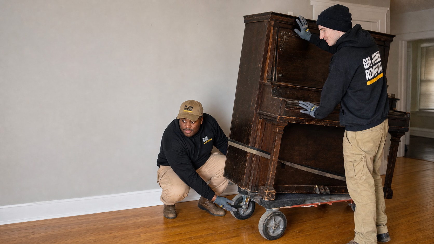 Two crew members moving an upright piano